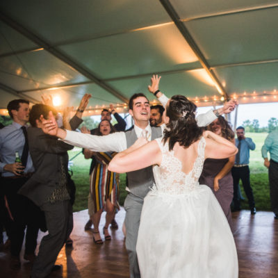 bride dancing with guests on the dance floor under the reception tent