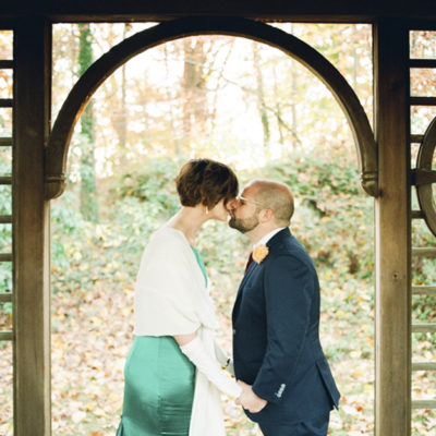 bride and groom kiss in a rain shelter in the gotelli conifer collection