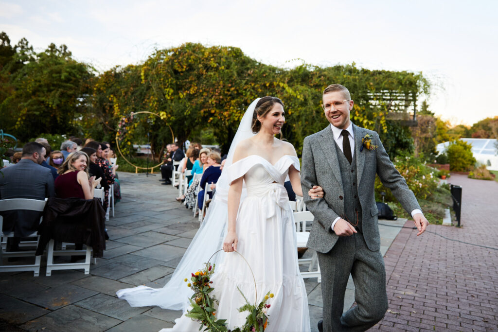 Bride and groom walking down the isle in the National Herb Garden