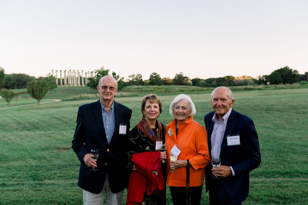 Dinner under the stars attendees stand in the meadow in front of the capitol columns