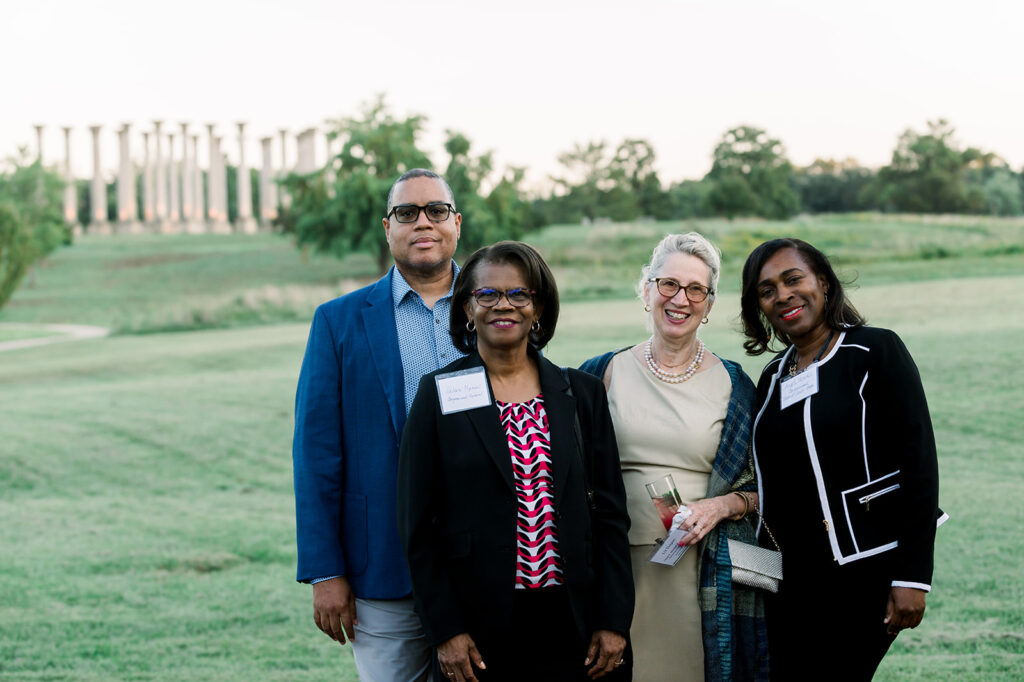 Dinner under the stars attendees stand in the meadow in front of the capitol columns