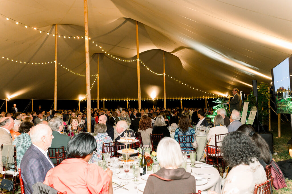 dinner under the stars attendees listen to a speaker while eating dinner