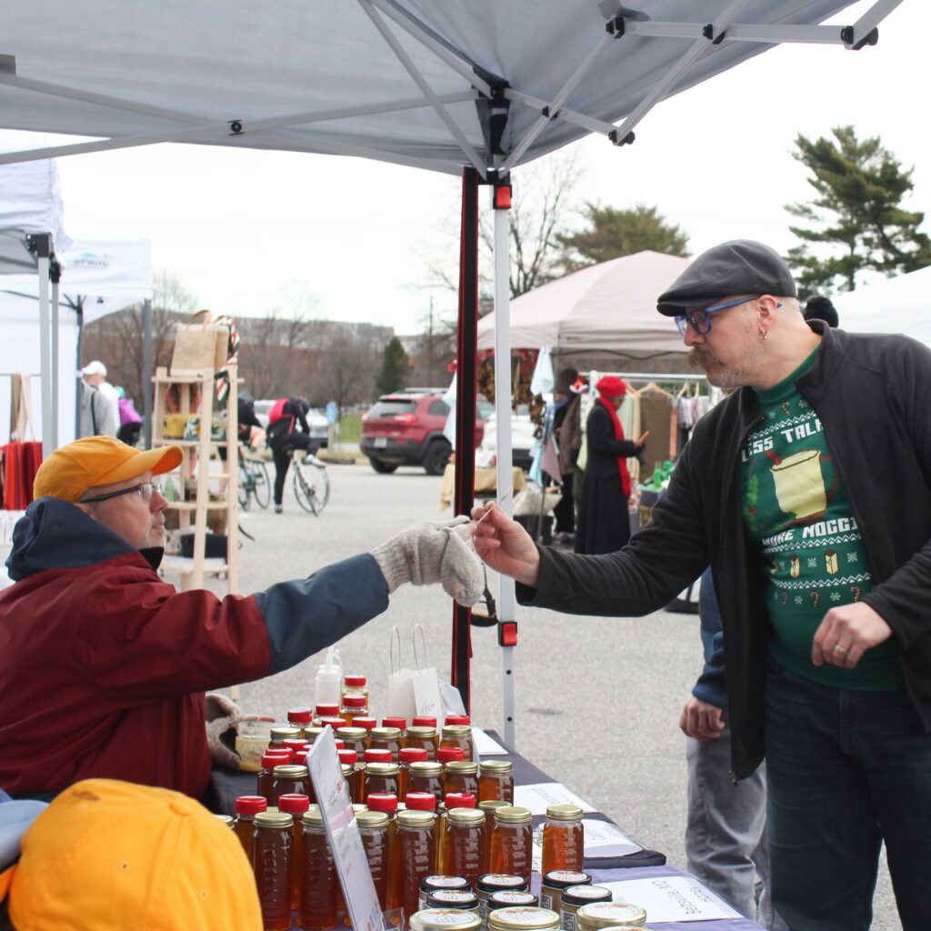 winter festival attendee tries honey from a vendor