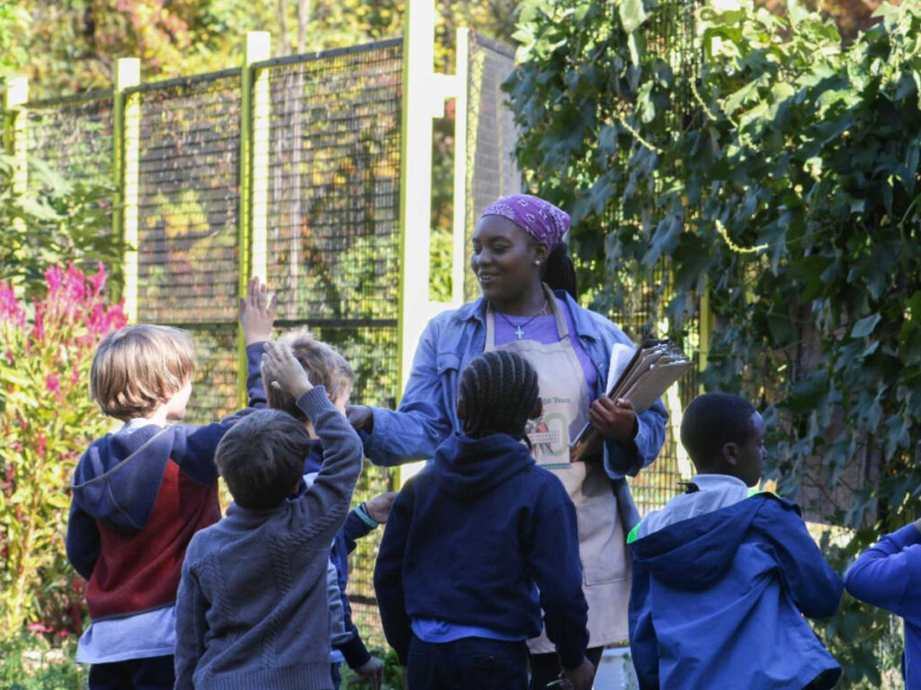 Students raising their hands at a SPROUT field trip in the Washington Youth Garden