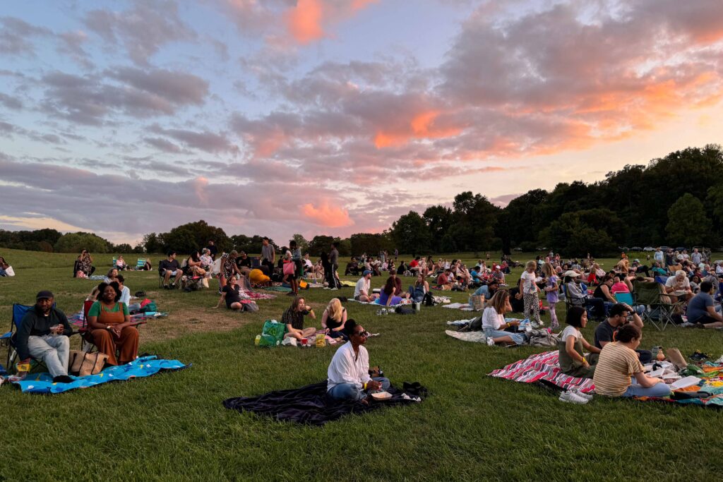 Music in the Meadow concert attendees sitting in the Ellipse Meadow at sunset