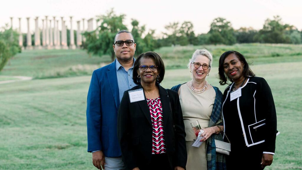 Dinner under the stars attendees stand in the meadow in front of the capitol columns