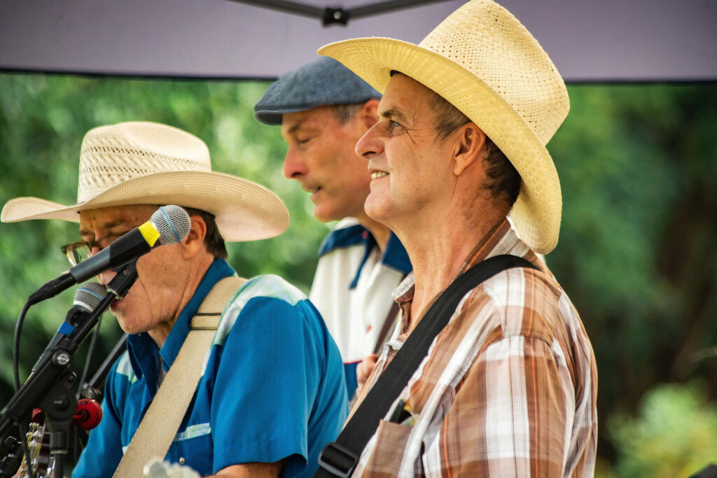 the three members of the buck forty nine band playing music in the meadow