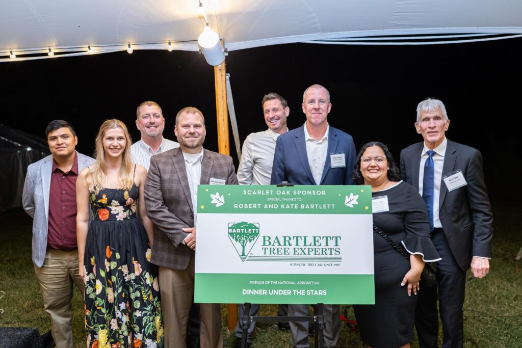 Bartlett Tree Experts team stand with the Bartlett sponsor sign at the Dinner Under the Stars