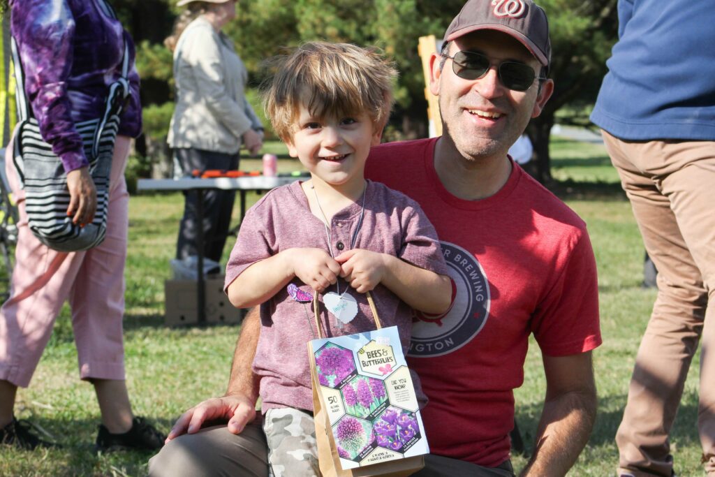 young child holding a bag of bulbs, with his guardian behind him
