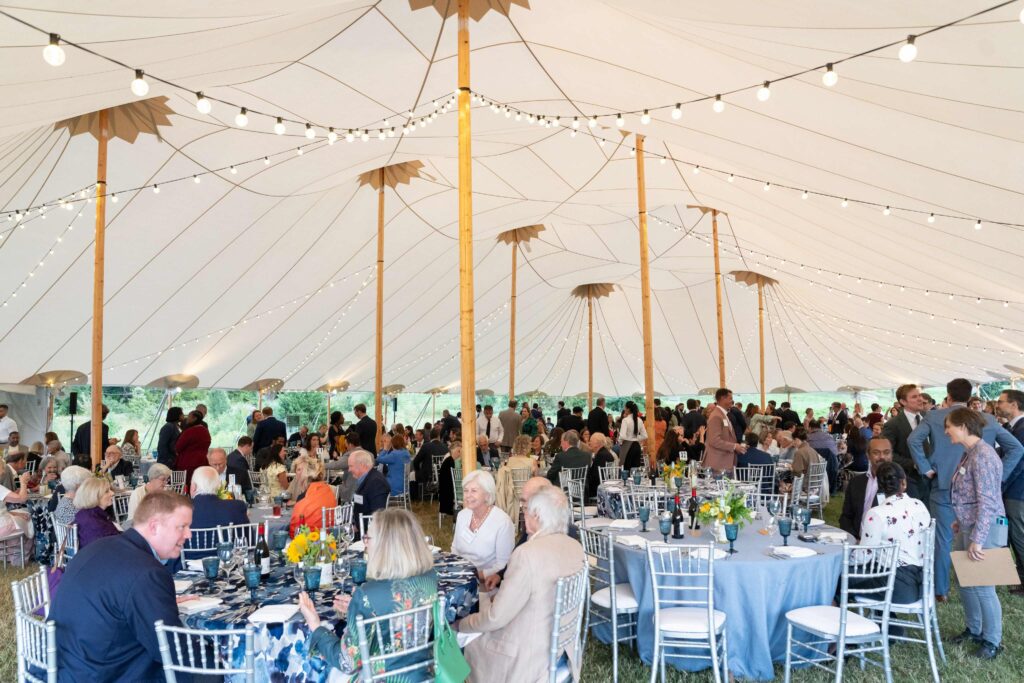 Dinner Under the Stars guests sitting at tables and standing talking under a tent