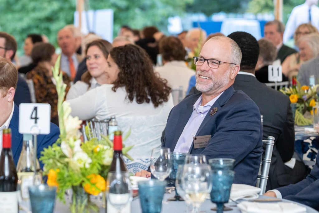 Dr. Richard T. Olsen smiling at a table at Dinner Under the Stars
