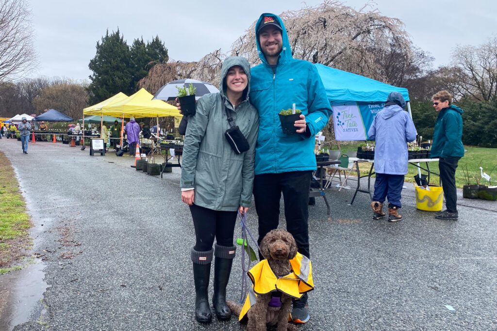 visitors and their dog holding plants purchased from the native plant sale