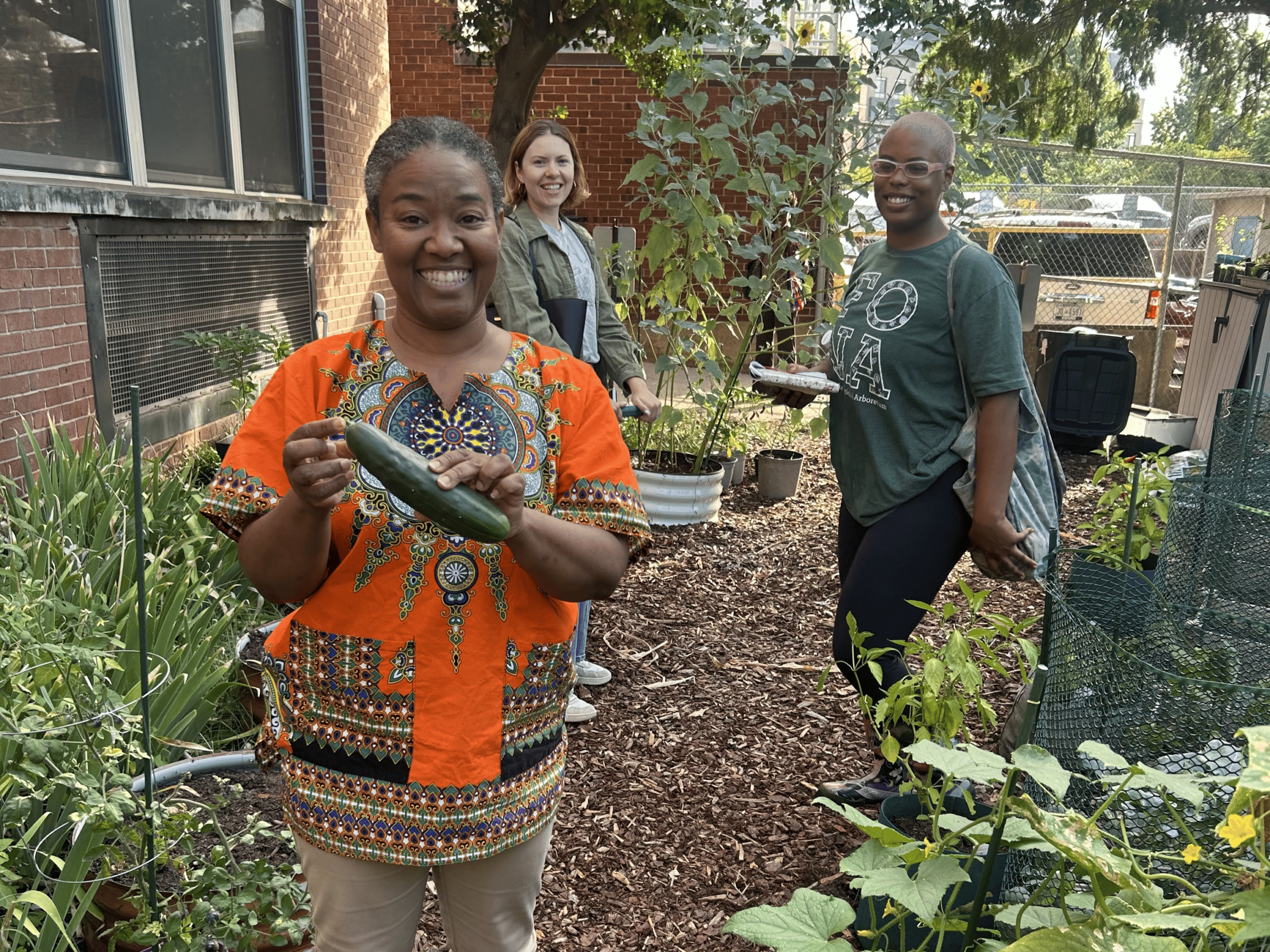 Teacher and staff pose with vegetables in the school garden