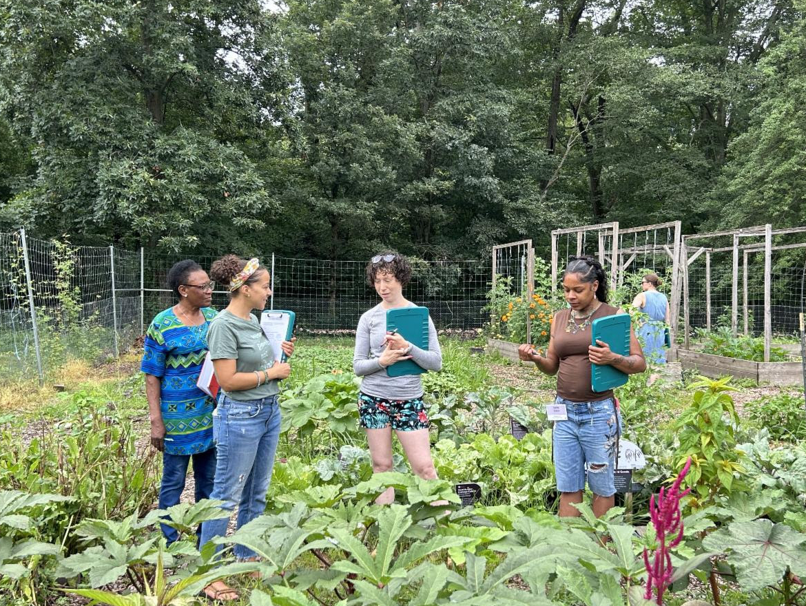 Educators stand holding clipboards and chatting in the Washington Youth Garden at the U.S. National Arboretum