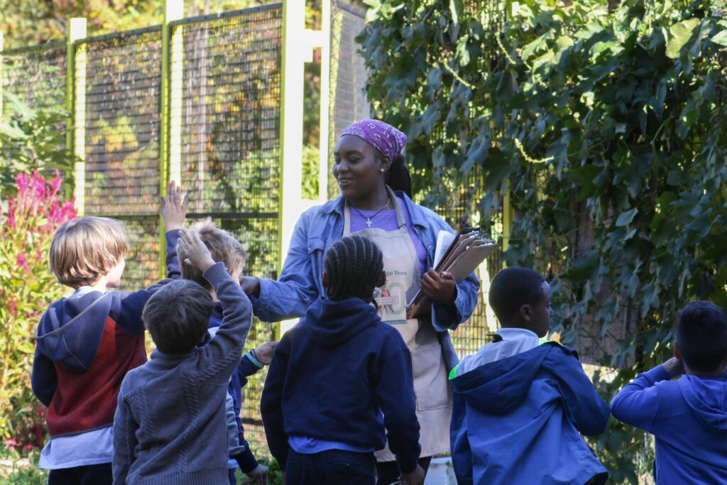 Students raising their hands at a SPROUT field trip in the Washington Youth Garden