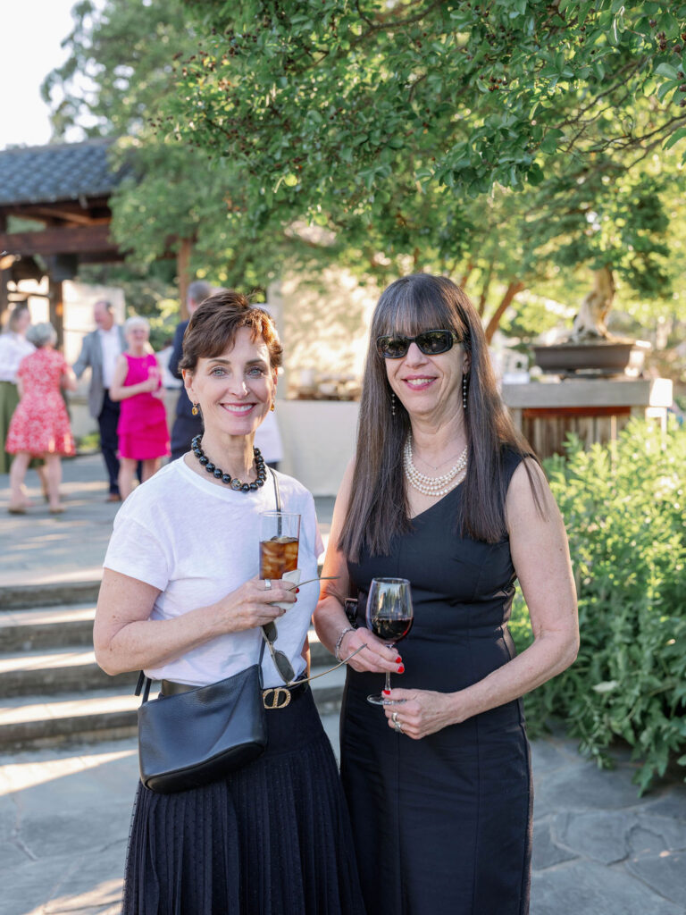 Guests at the 2026 spring soiree in the national bonsai and penjing museum, smiling at the camera and holding a drink