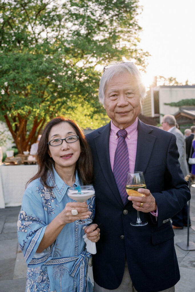 Guests at the 2026 spring soiree in the national bonsai and penjing museum, smiling at the camera and holding a drink