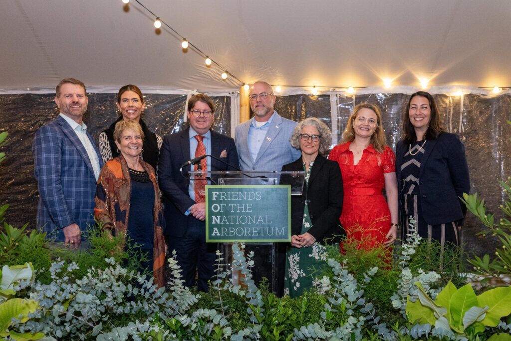 Dinner under the stars attendees posing in front of the event podium. From left: Chandler Goule, Amy Titus, Anne MacMillan, Deputy Secretary Stephen Vaden, Dr. Richard Olsen, Jeanne Braha, Martha Van Dale, Virginia Kromm.